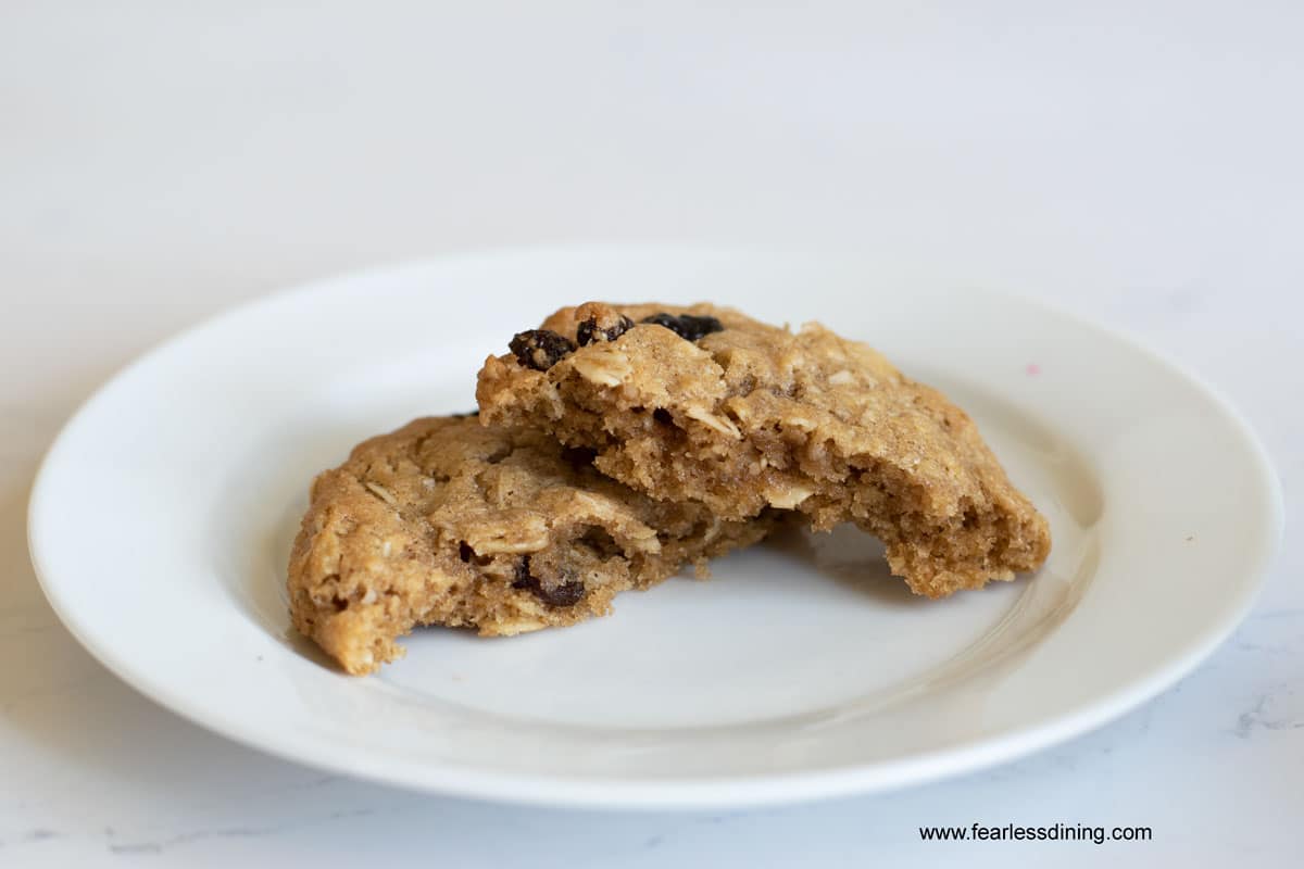 An oatmeal raisin cookie broken in half on a plate.