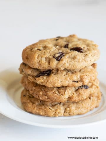 A stack of four oatmeal raisin cookies on a plate.