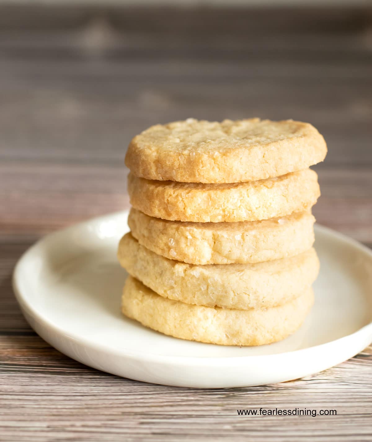 A stack of 5 gluten free sable cookies on a white plate.