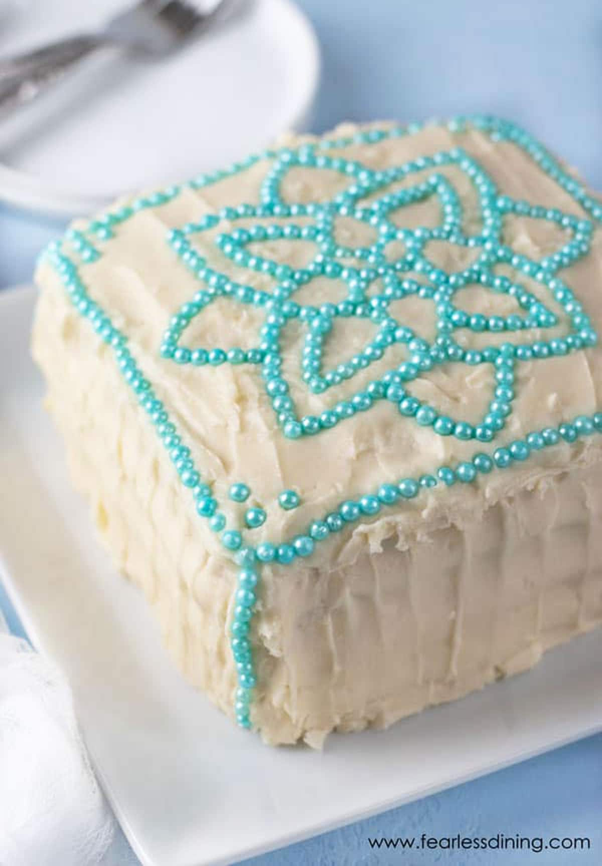 A cake decorated with turquoise bead-like sprinkles.