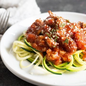 A plate full of zucchini noodles topped with the pork pasta sauce.