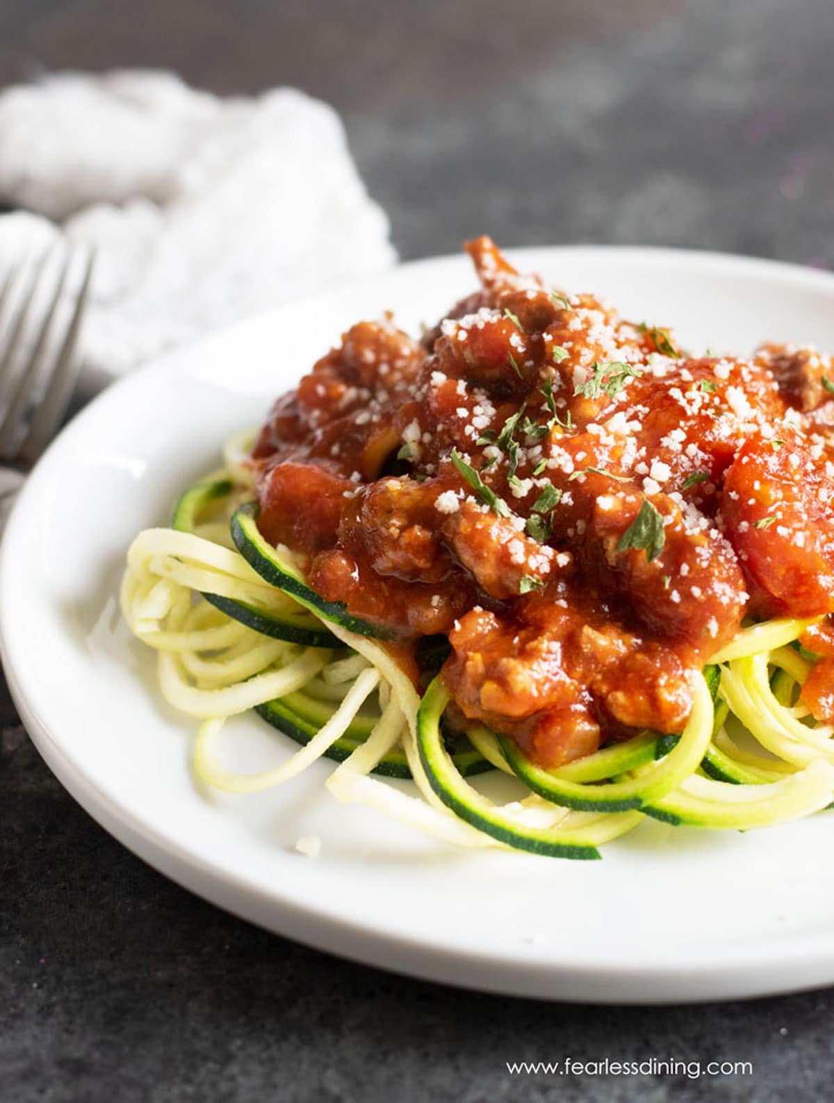 A plate full of zucchini noodles topped with the pork pasta sauce.