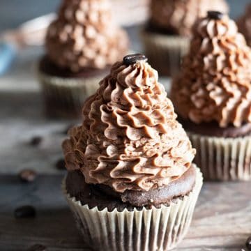 Rows of frosted mocha cupcakes on a wooden table.