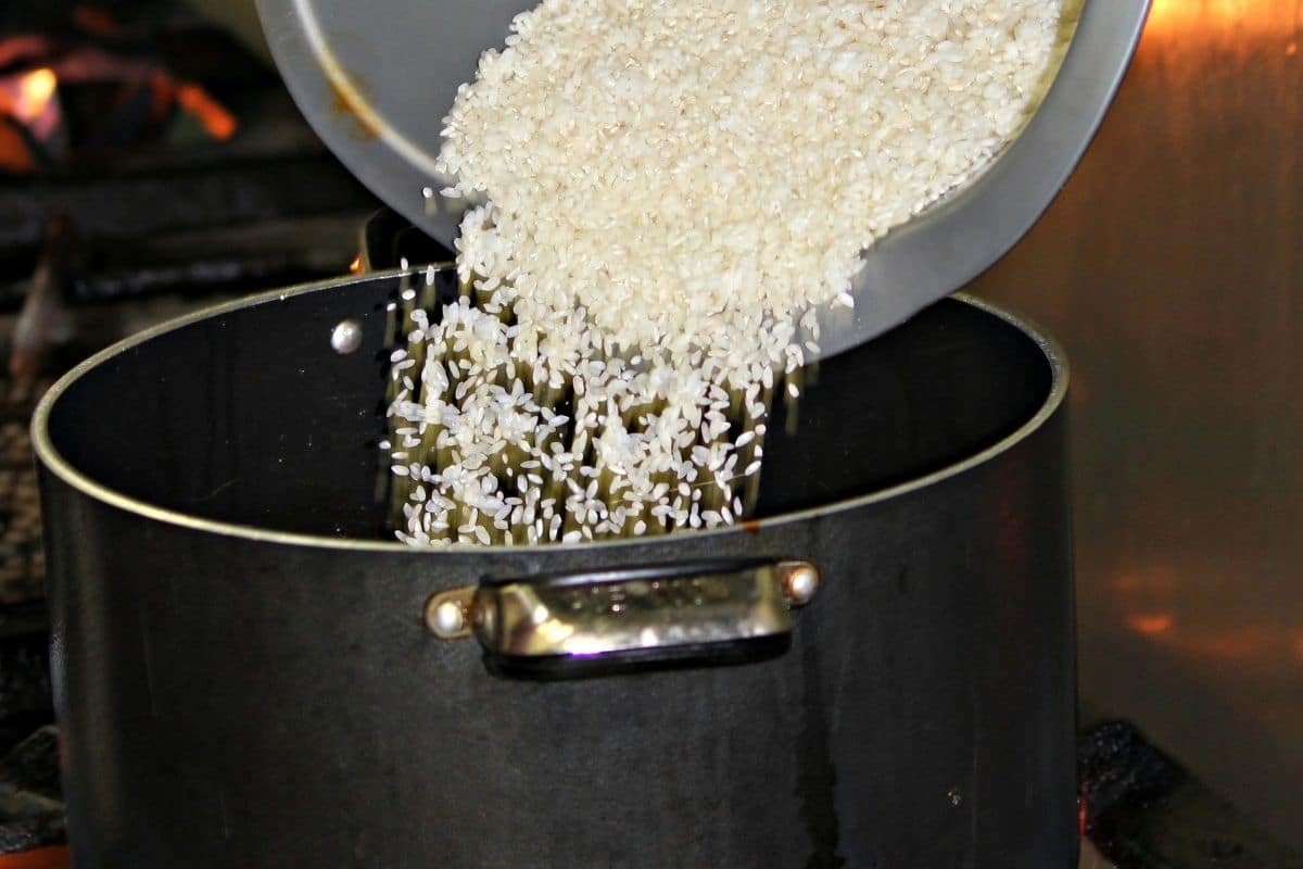 Pouring short grain white rice into a black pot.