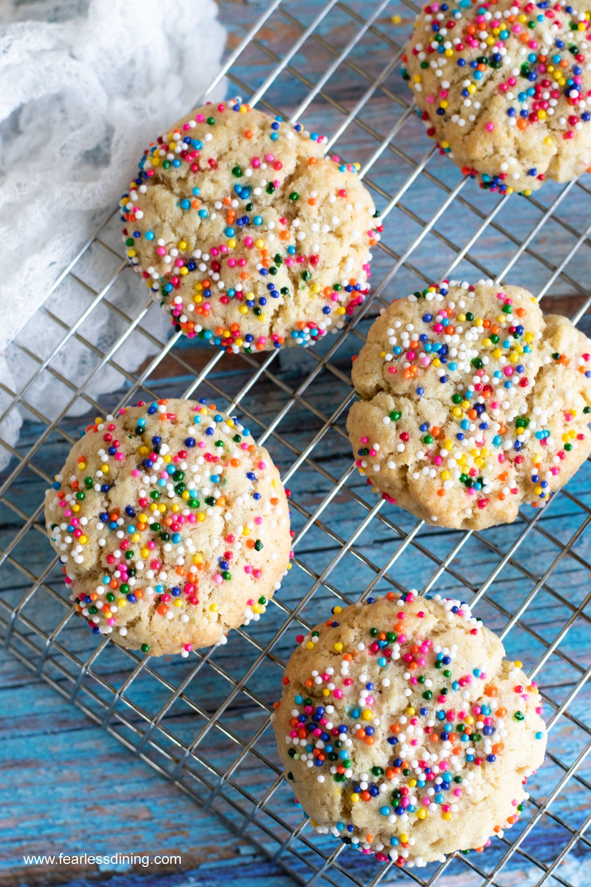 The a cooling rack with sprinkles cookies.