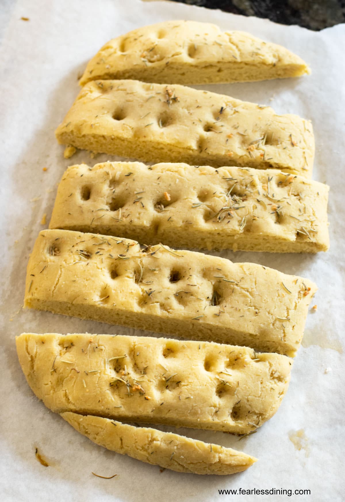 Freshly baked gluten free focaccia on a cookie sheet with slices.