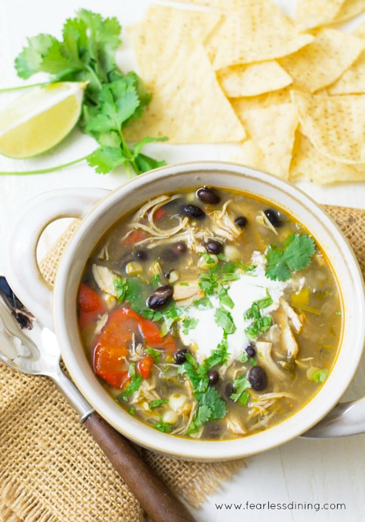 A top view of a bowl of taco soup with corn tortilla chips.