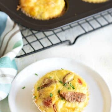 A sausage stuffed egg muffin cup on a white plate.