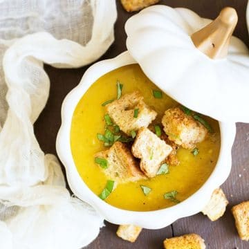 the top view of a white pumpkin shaped bowl filled with acorn squash soup