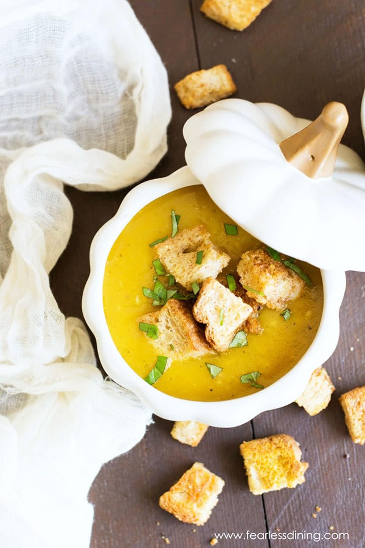 The top view of a white pumpkin shaped bowl filled with acorn squash soup.