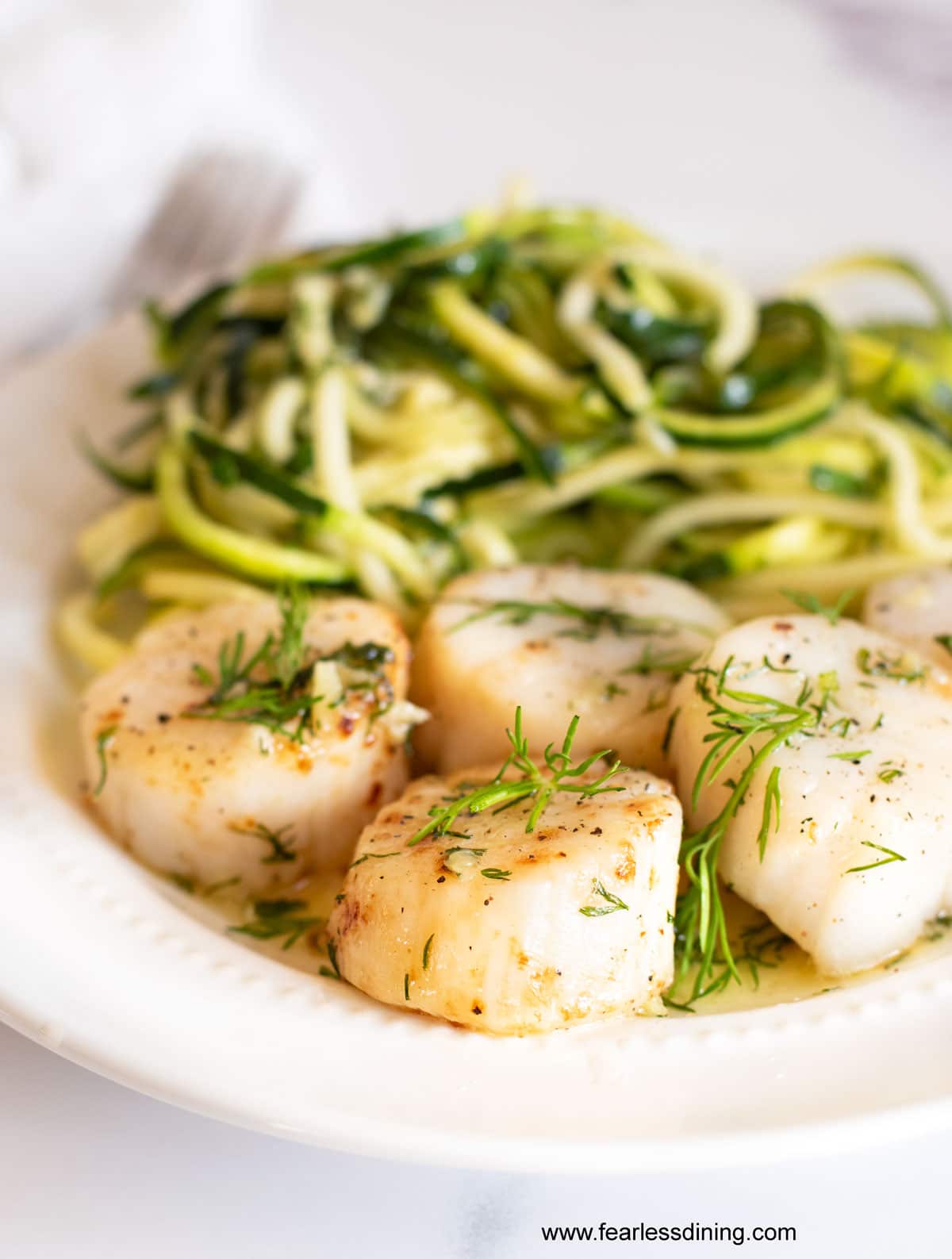 A plate of air fried scallops and zoodles with a garlic butter sauce.