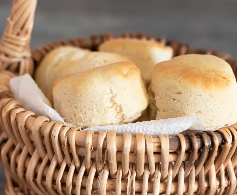 A close up of the baked gluten free rolls in a wicker bread basket.