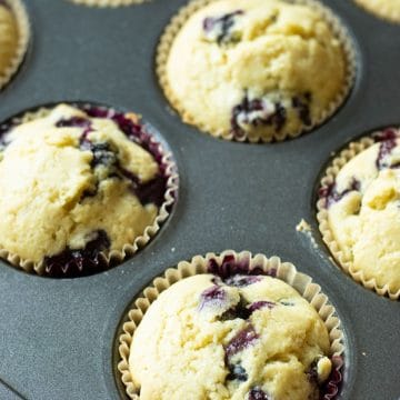 A muffin tin filled with baked gluten free blueberry muffins.