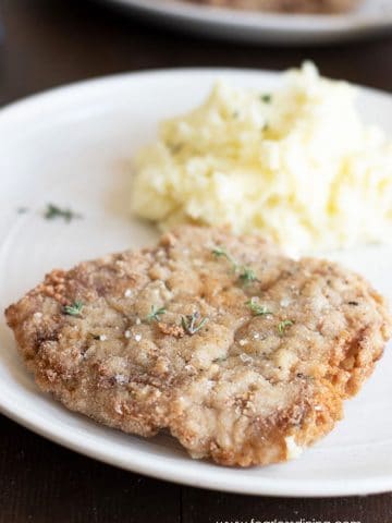 a piece of gluten free chicken fried steak on a plate with mashed potatoes