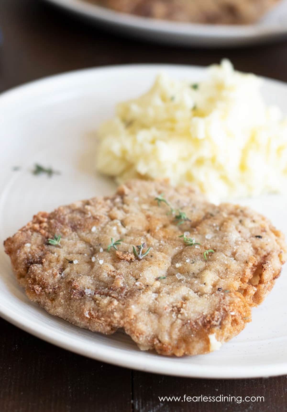 a piece of gluten free chicken fried steak on a plate with mashed potatoes