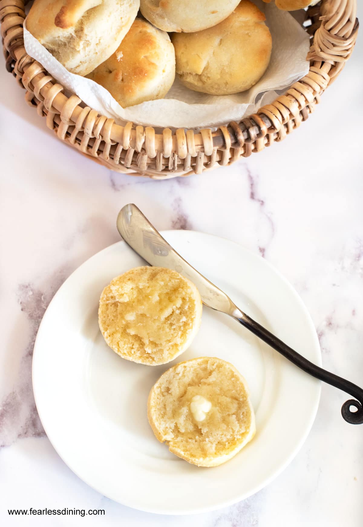 a gluten free dinner roll cut in half with butter on each half