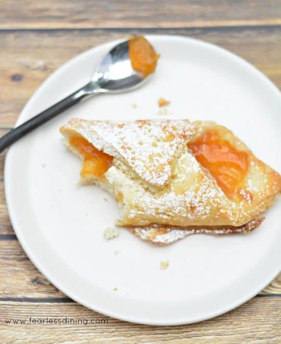 A gluten free pastry on a white plate. A piece was cut off with a fork.