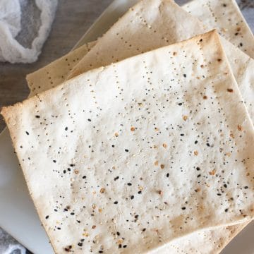 Whole pieces of homemade gluten free matzo on a plate.