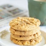 a stack of four peanut butter cookies next to a mug of coffee