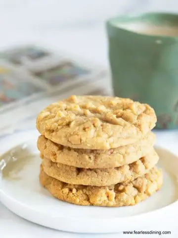 a stack of four peanut butter cookies next to a mug of coffee