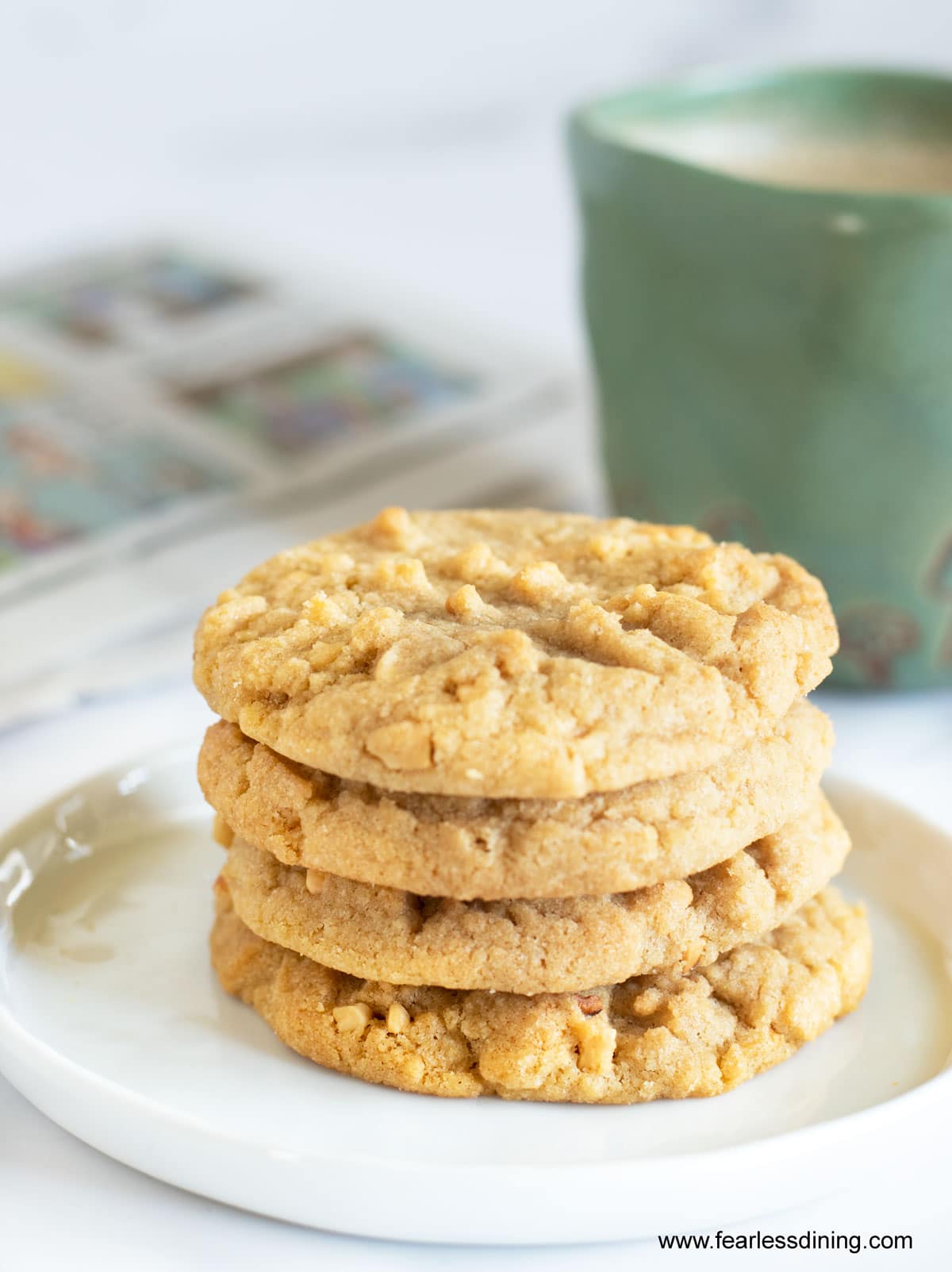 A stack of four peanut butter cookies next to a mug of coffee.