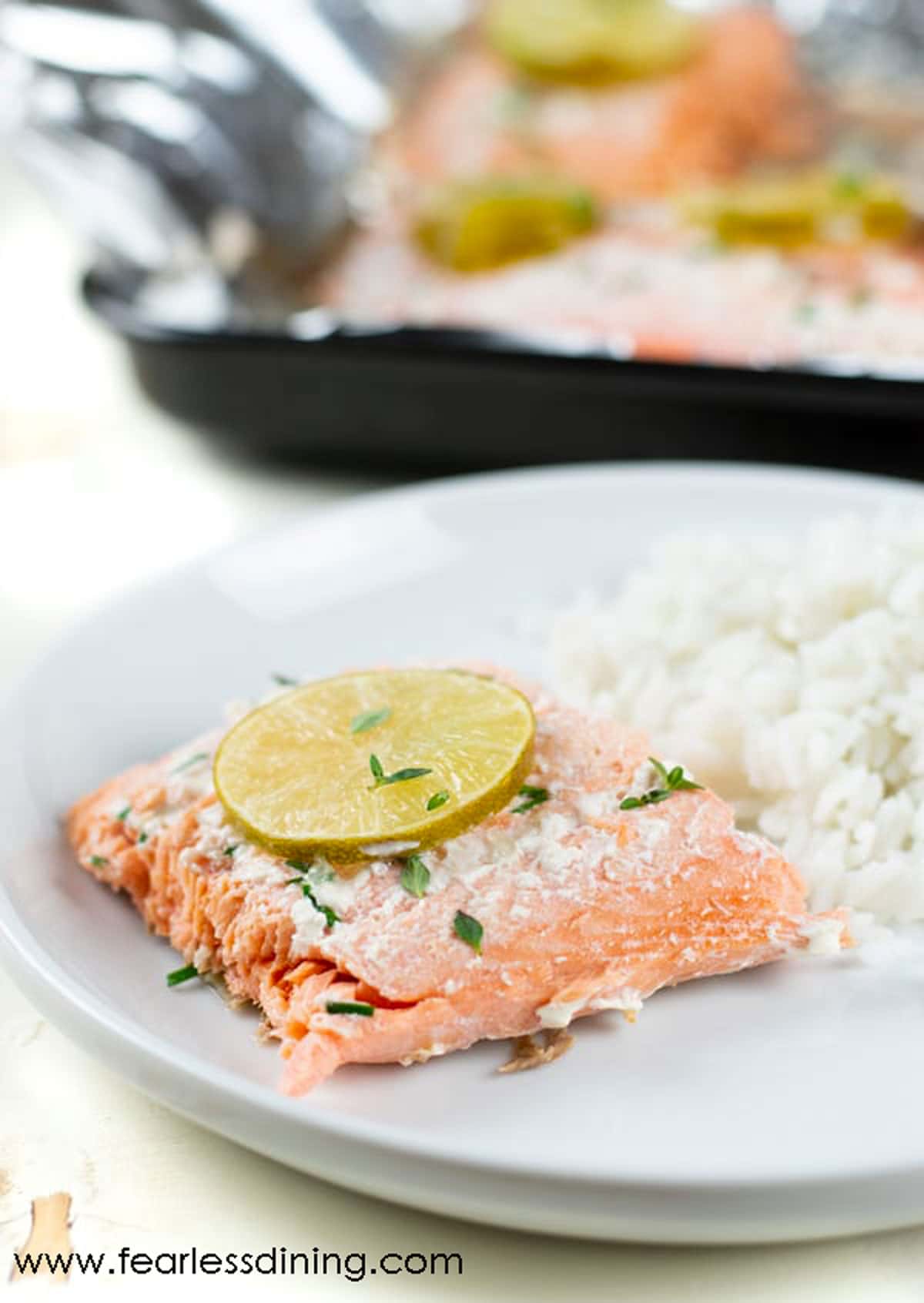 A slice of cooked salmon with rice on a white plate.