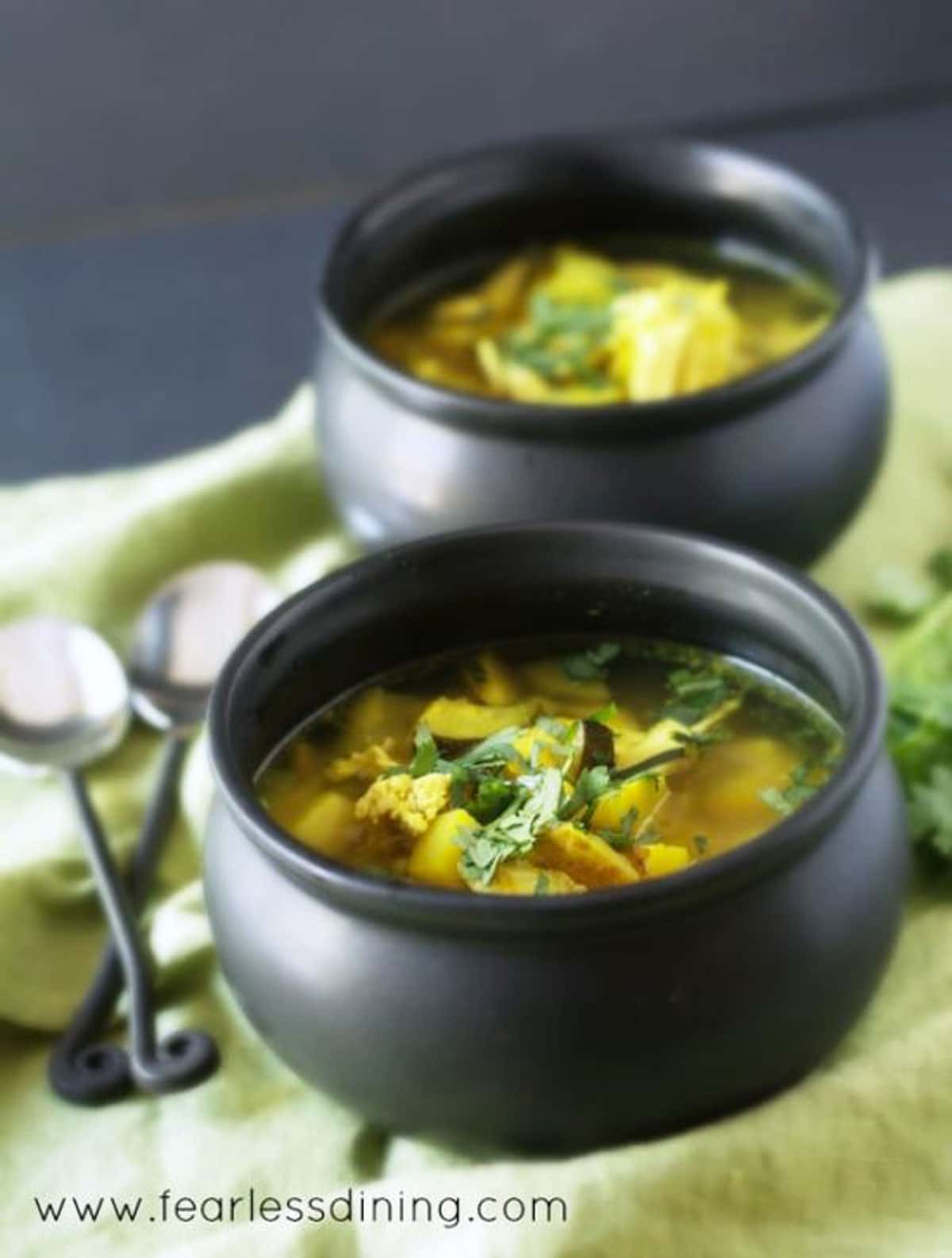 Two black bowls filled with chicken turmeric soup.