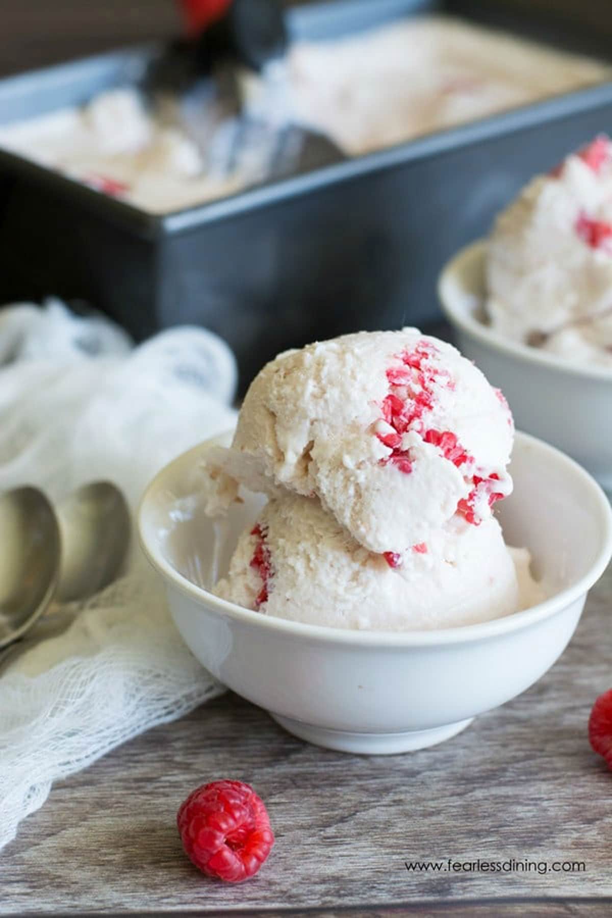 A scoop of white chocolate raspberry ice cream in a small white bowl.
