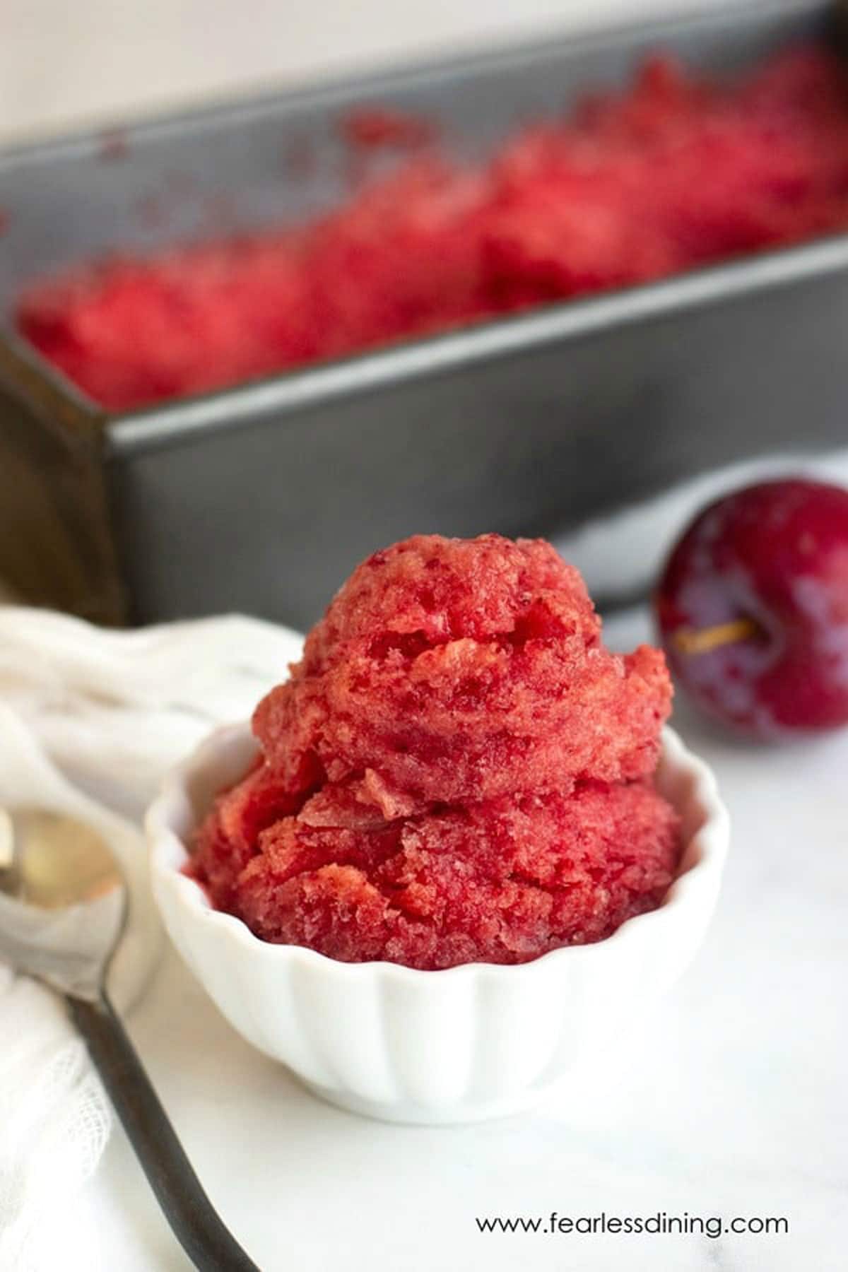 A scoop of plum sorbet in a small white bowl.