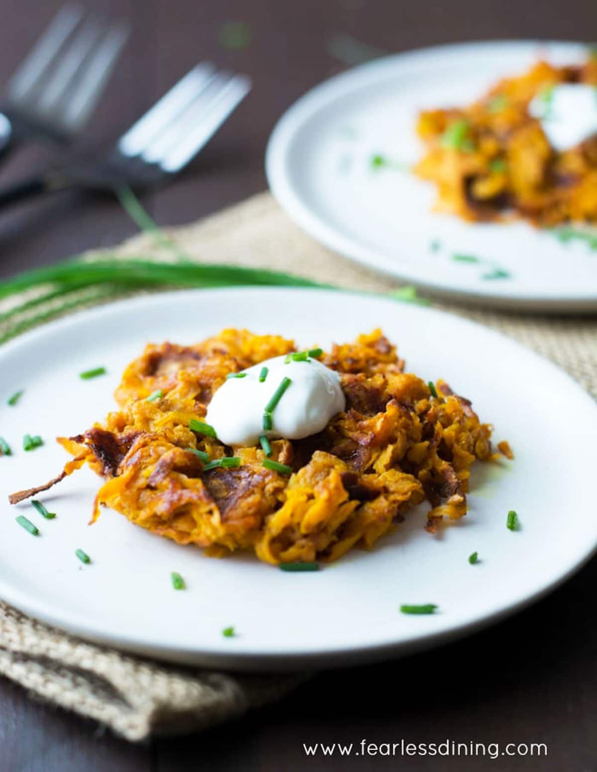 Sweet potato waffles on white plates, garnished with sour cream and chives.