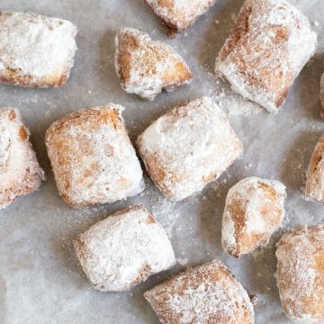 The top view of a bunch of powdered sugar coated beignets.