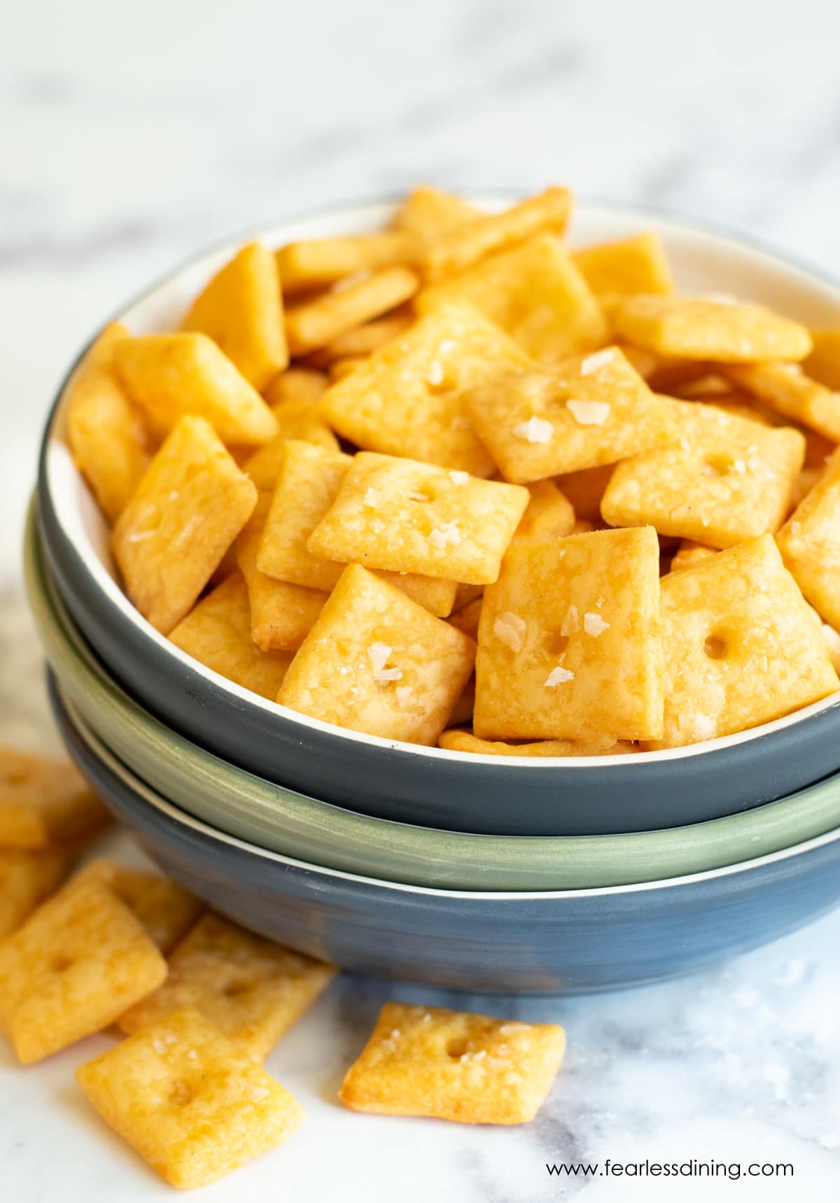 A blue bowl filled with gluten free cheez its on the counter.