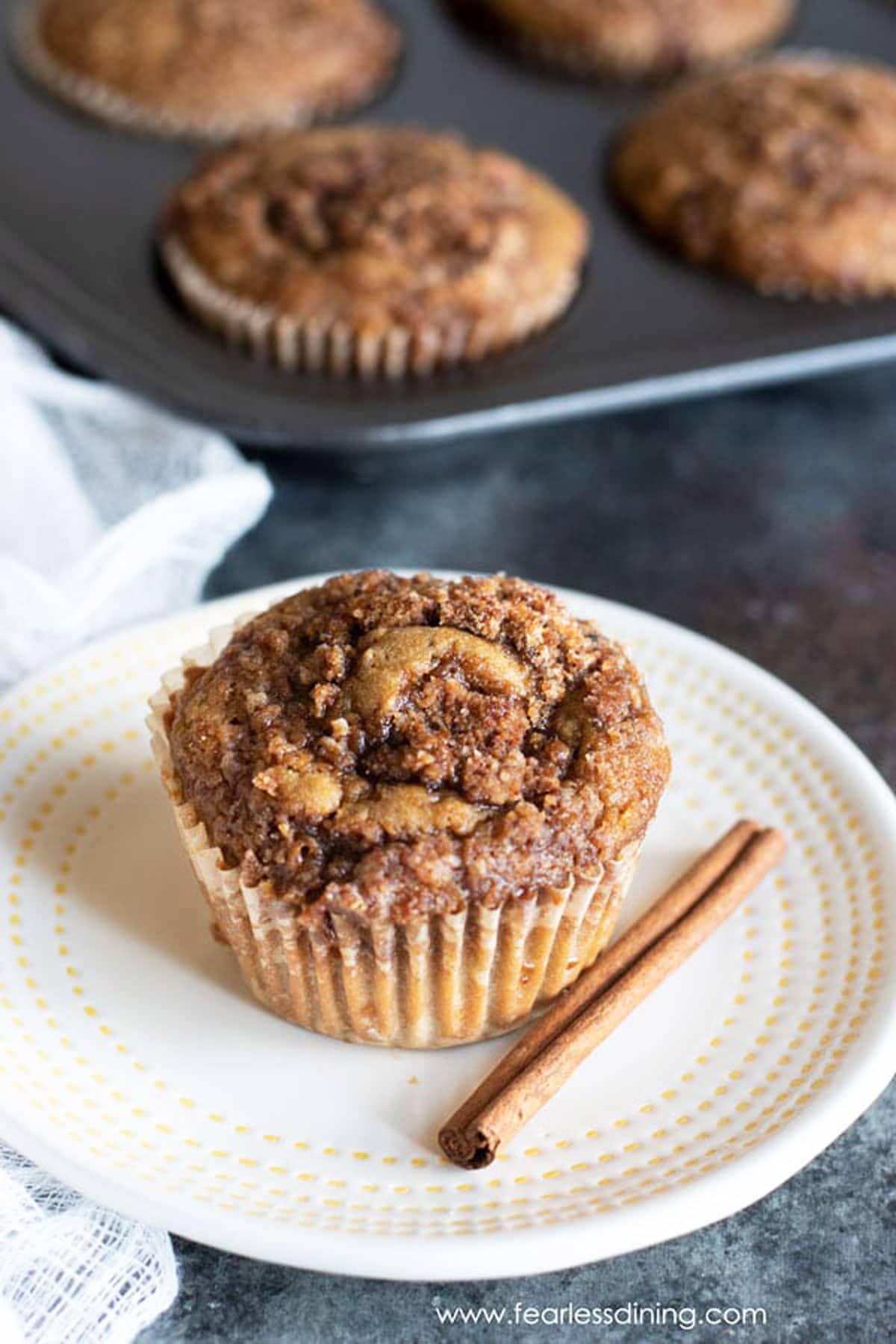 A gluten free cinnamon streusel muffin on a small white plate.