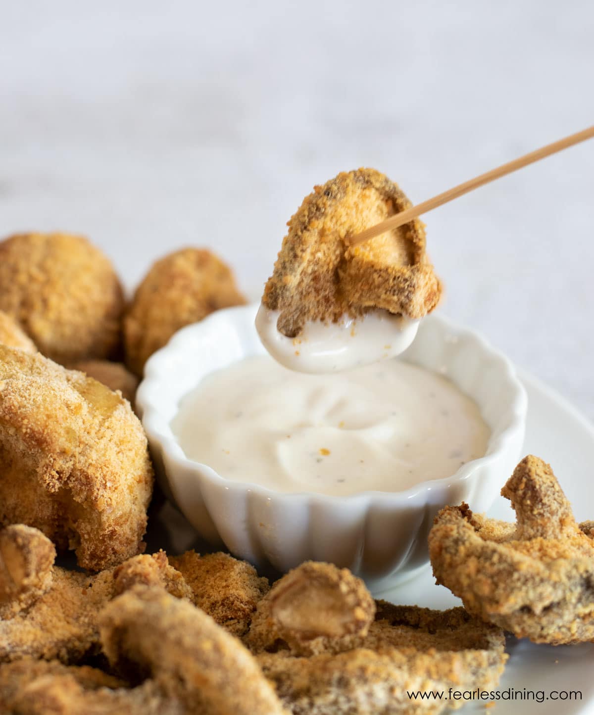 Dipping a fried mushroom in ranch dressing.