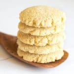 A stack of five lemon cookies on a large flat wooden spoon.