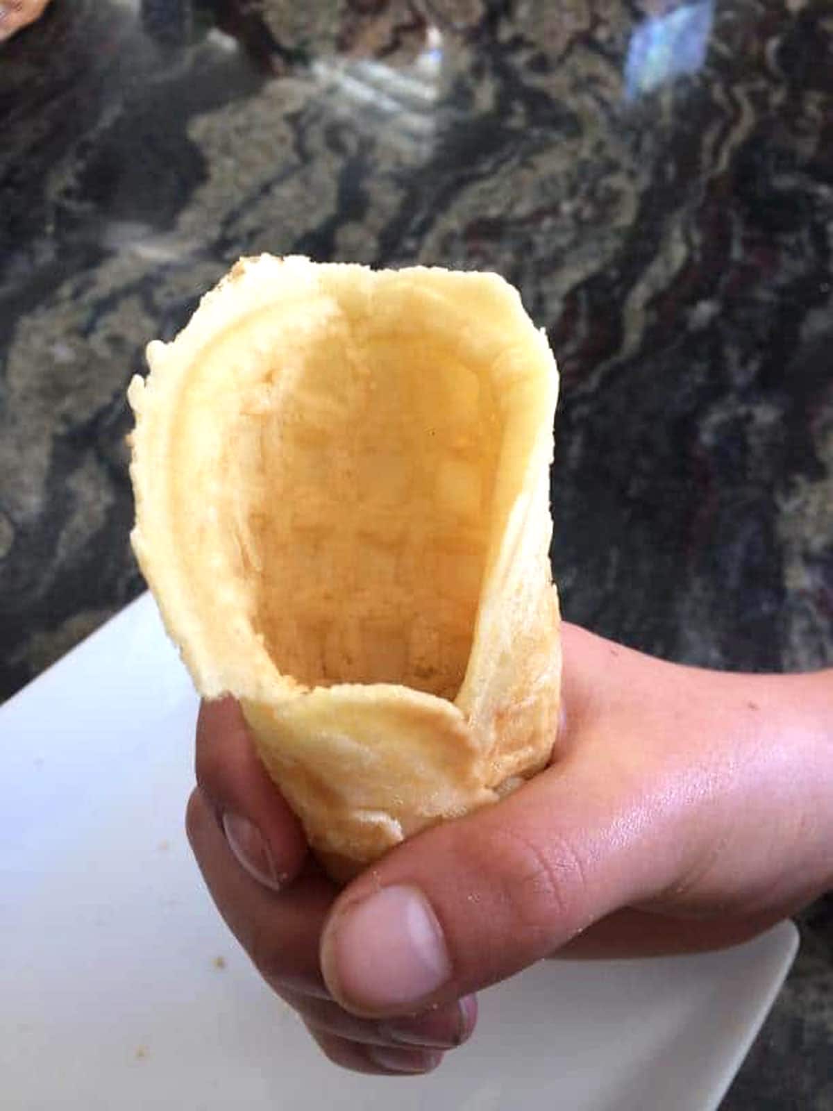 A hand holding a diy gluten free waffle cone.