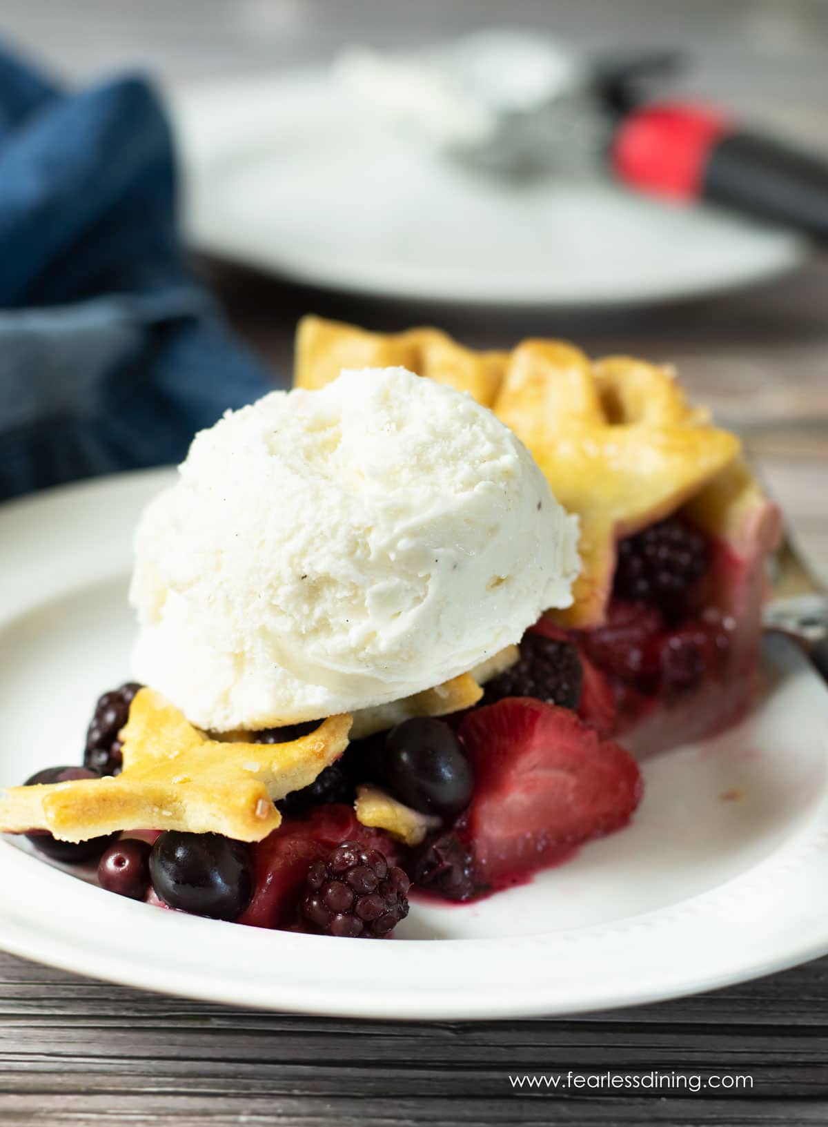 A slice of mixed berry pie with a scoop of ice cream on top.