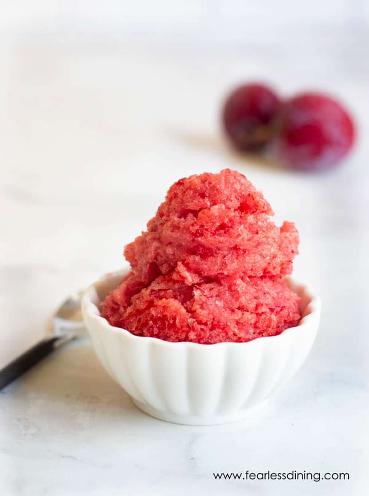 The frozen plum sorbet in a scalloped white bowl.