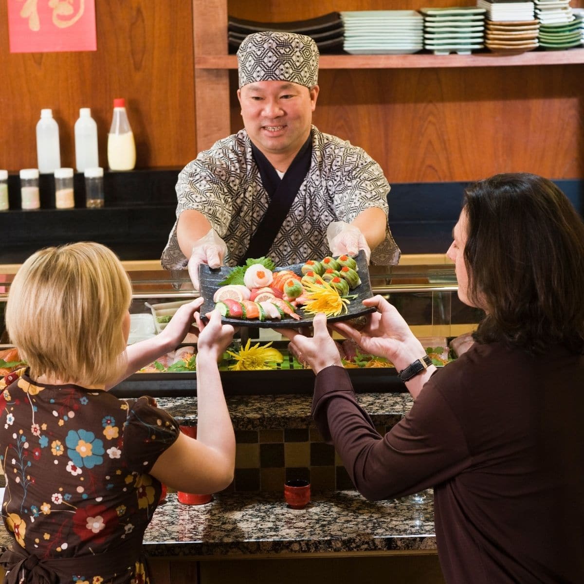 A couple being served in a sushi restaurant.