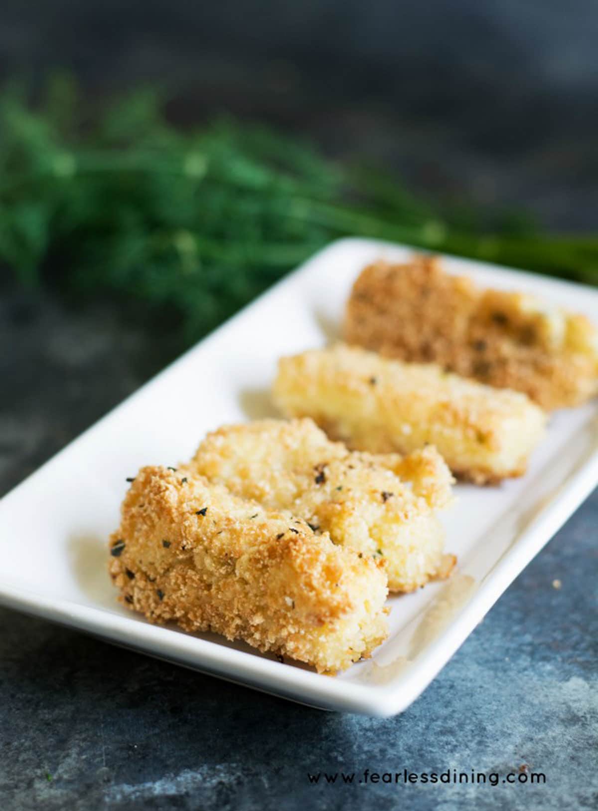 A rectangular white plate with fried cheese sticks.