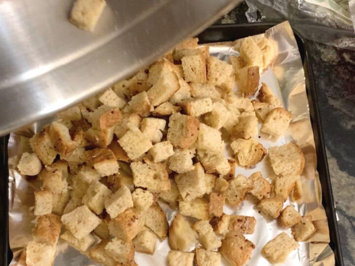 Pouring croutons onto a baking sheet.