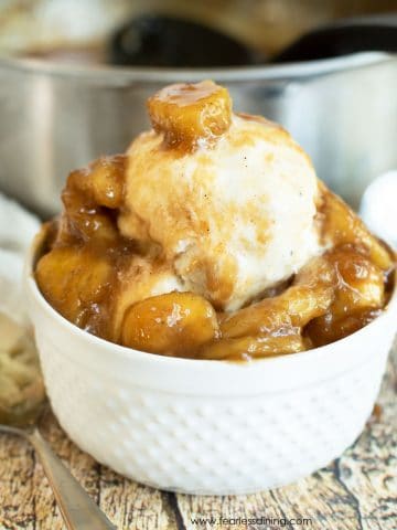 A white bowl filled with ice cream and caramelized bananas.
