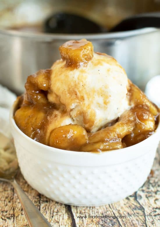 A white bowl filled with ice cream and caramelized bananas.