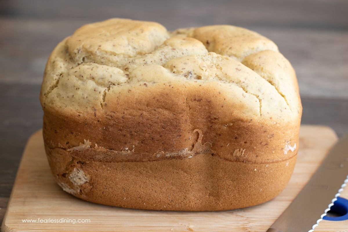 A whole loaf of gluten free bread on a cutting board.