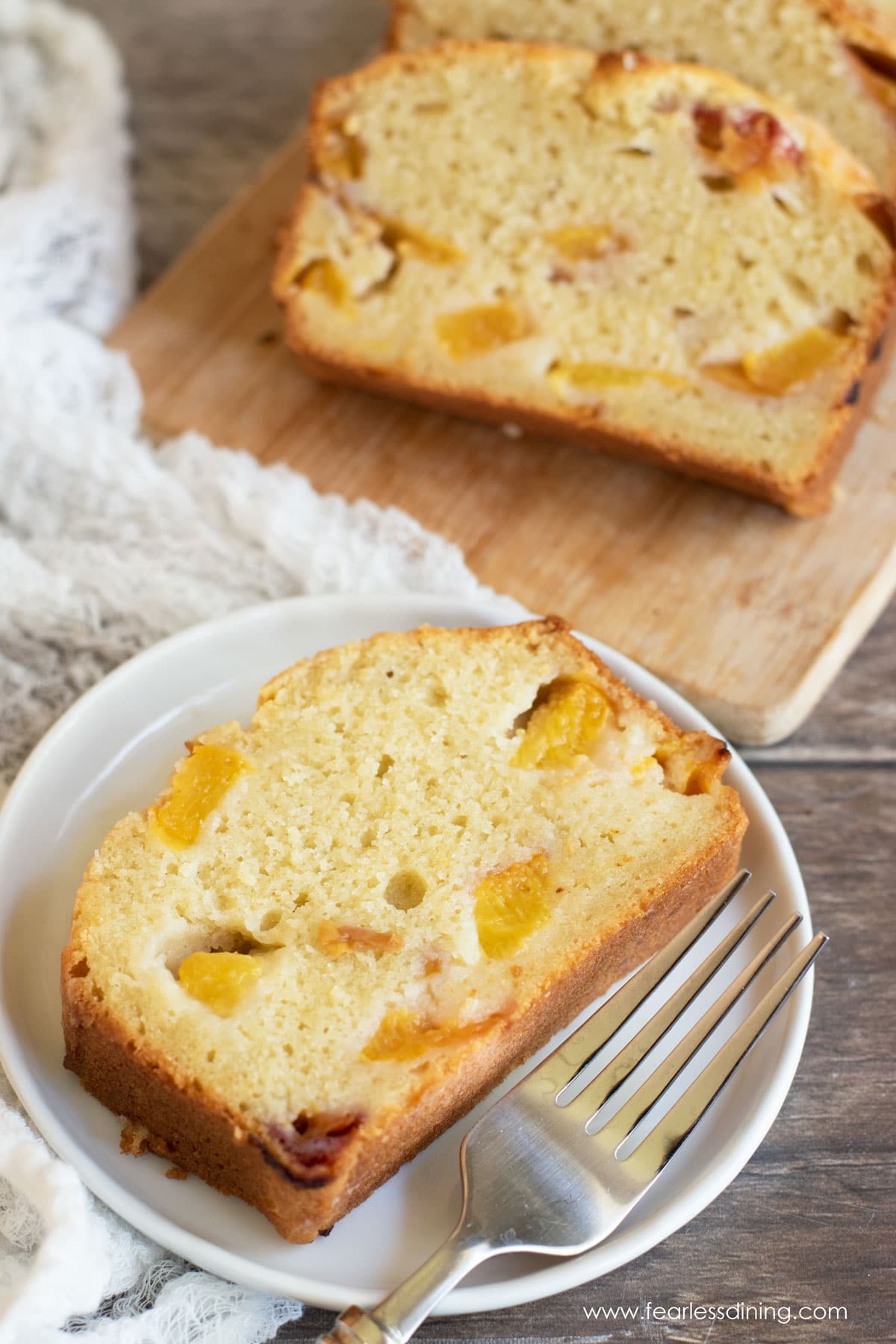 A slice of peach cake on a plate. A fork is next to the cake.