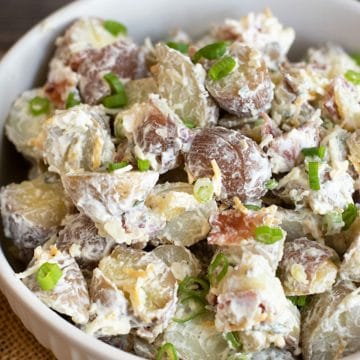 A white bowl filled with loaded baked potato salad.