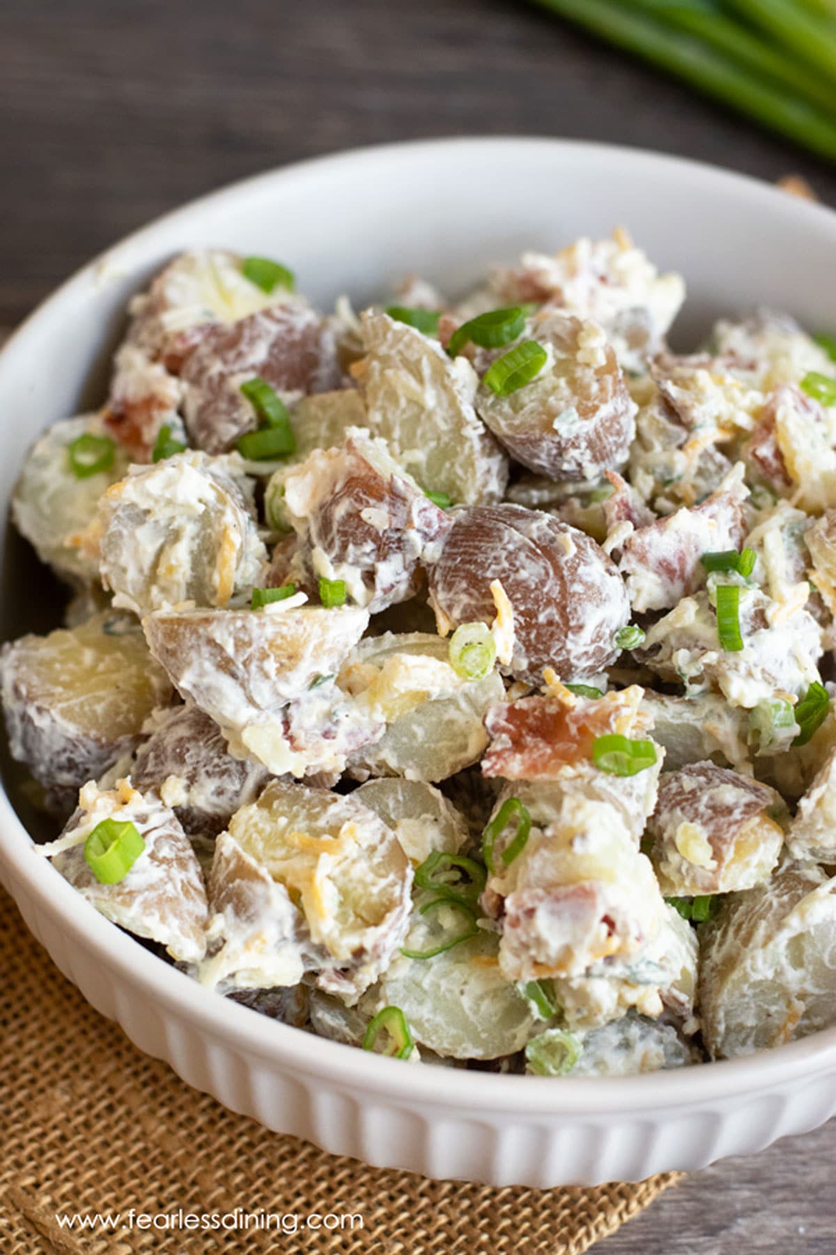 A white bowl filled with loaded baked potato salad.