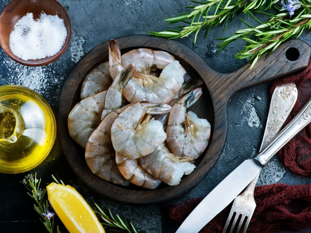 a wooden bowl with raw unpeeled shrimp