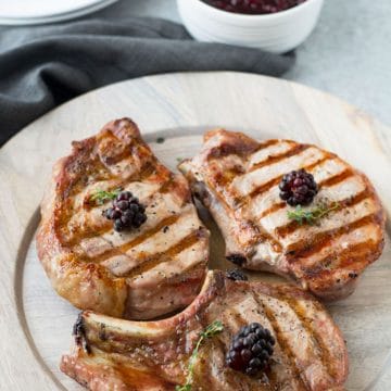 Grilled pork chops on a wooden plate.