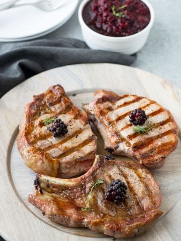 grilled pork chops on a wooden plate
